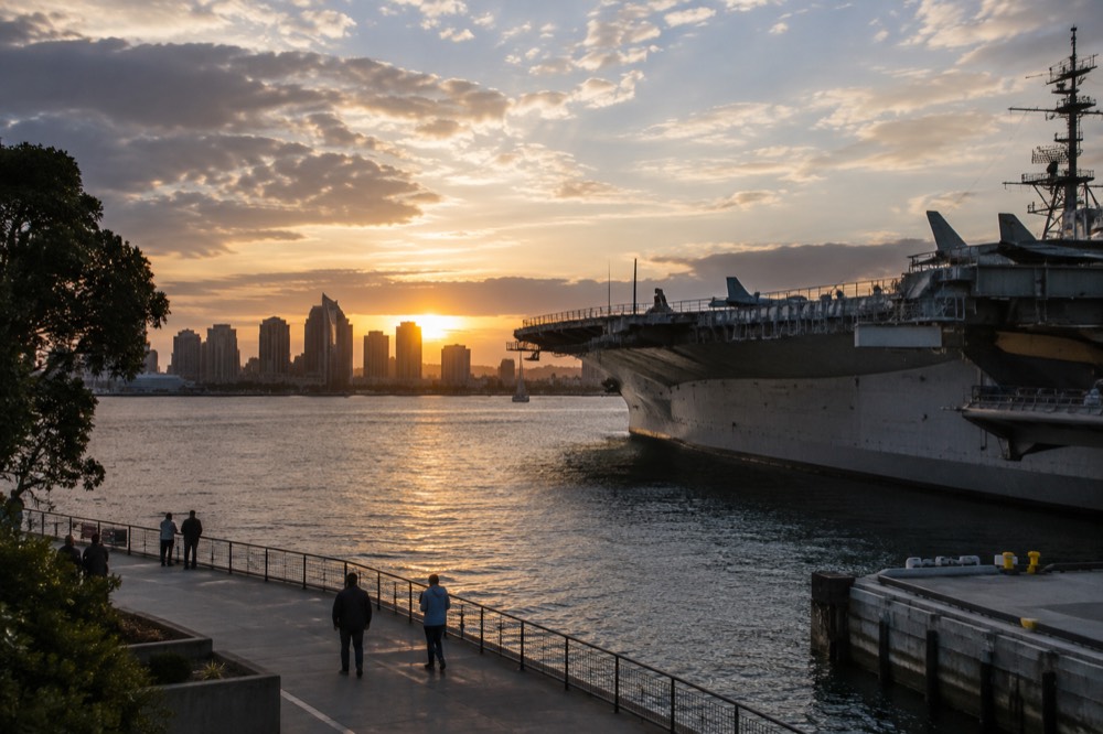 Sunset light over the bay with the aircraft carrier silhouette and city skyline in the background