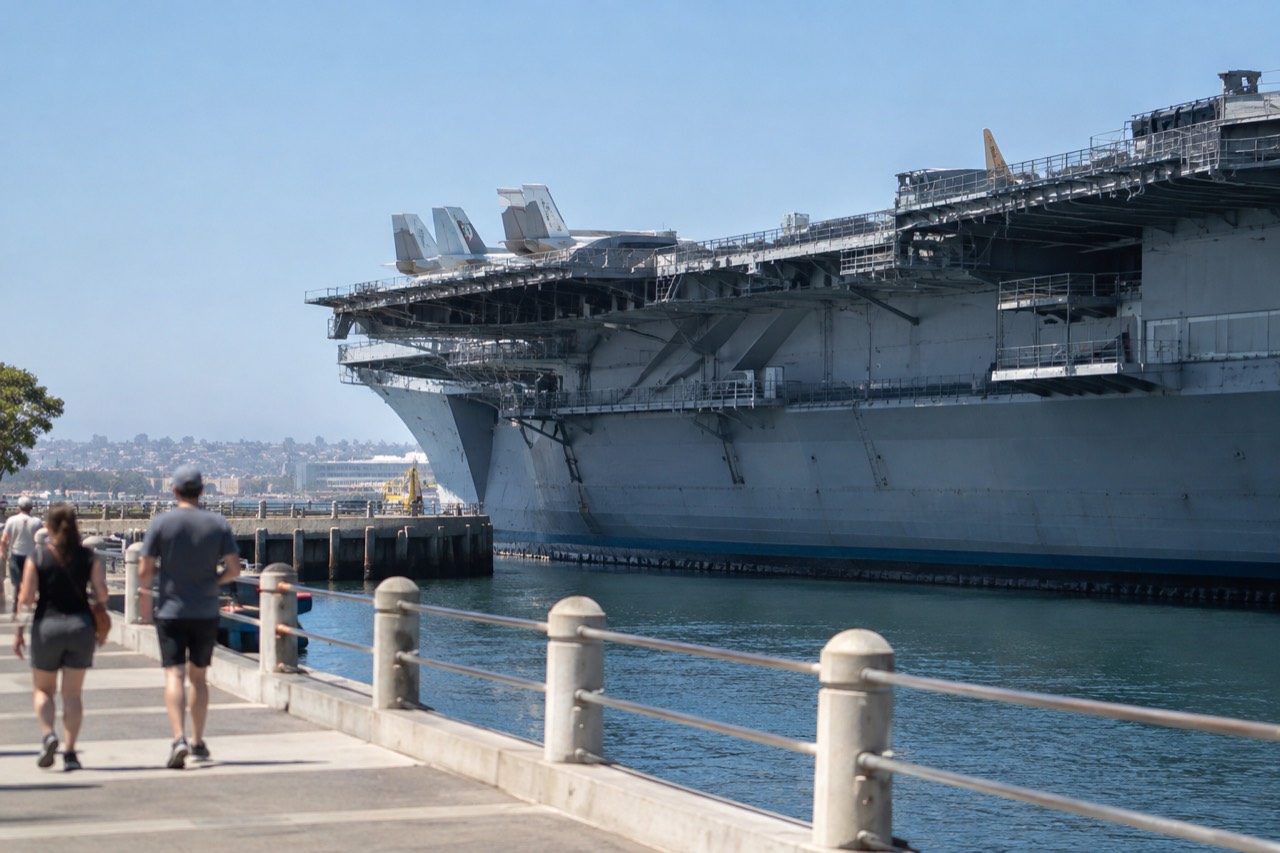 The USS Midway aircraft carrier moored at a downtown San Diego waterfront pier on a clear day