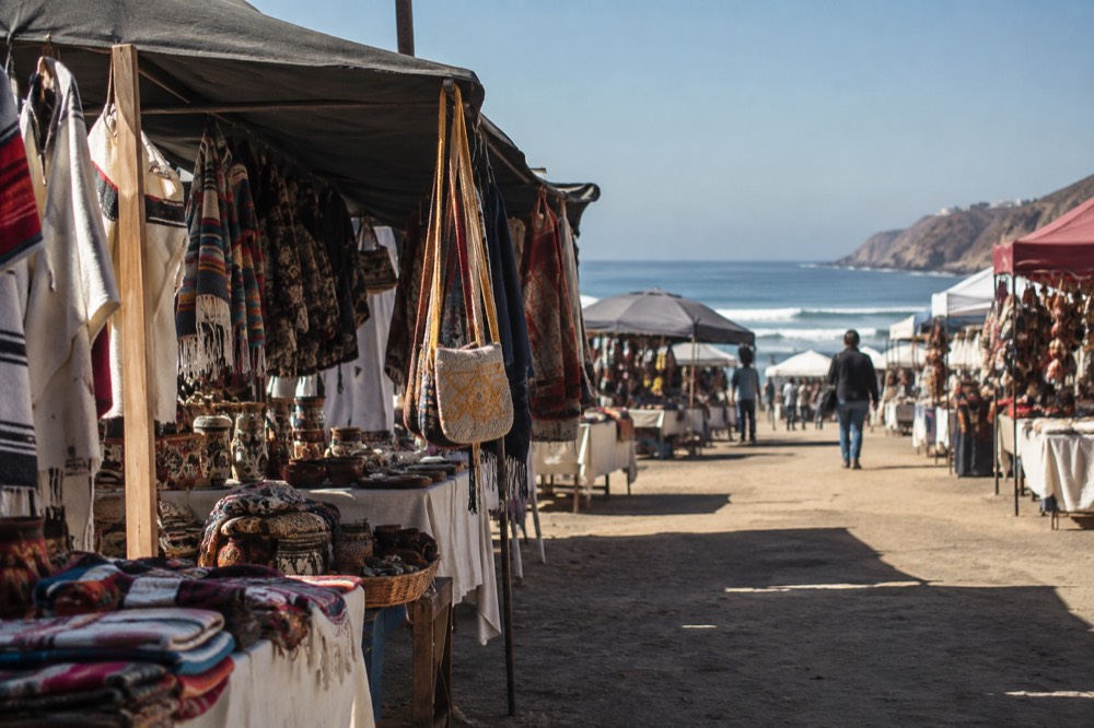 Open-air market stalls with handcrafted goods and colorful textiles displayed under awnings