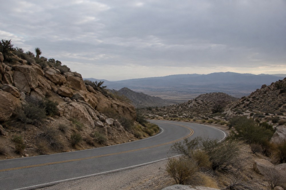 A winding mountain road with desert valley visible in the distance