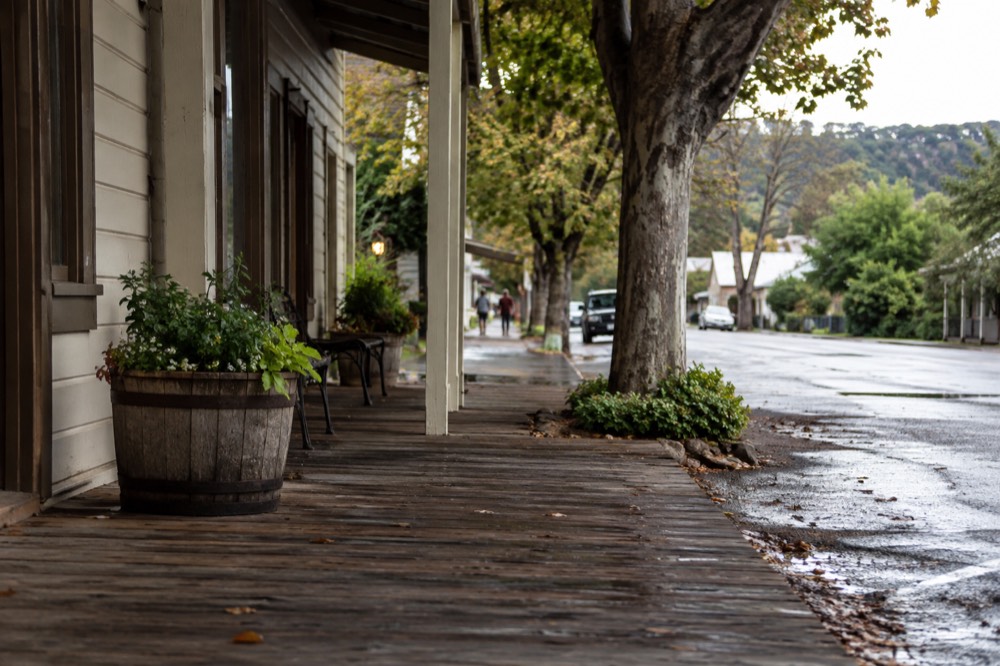 A quiet small town street with wooden sidewalks and trees