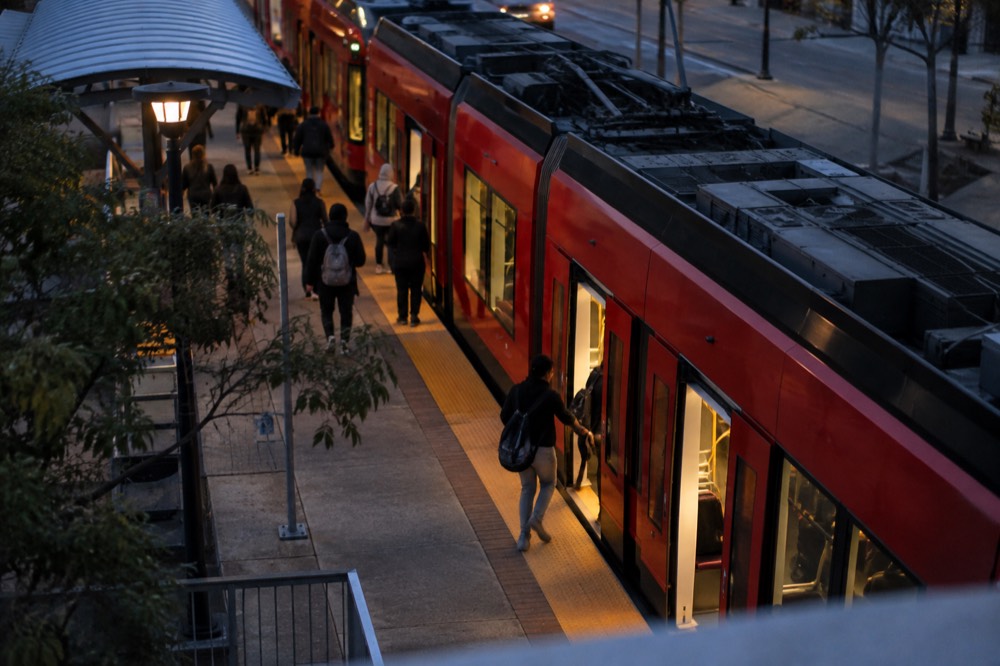 Red trolley car at a downtown San Diego station with passengers boarding