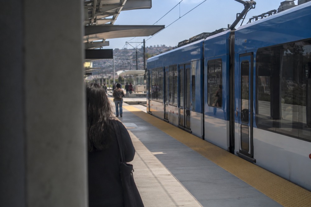 Blue Line trolley stopped at an outdoor station platform under a blue sky