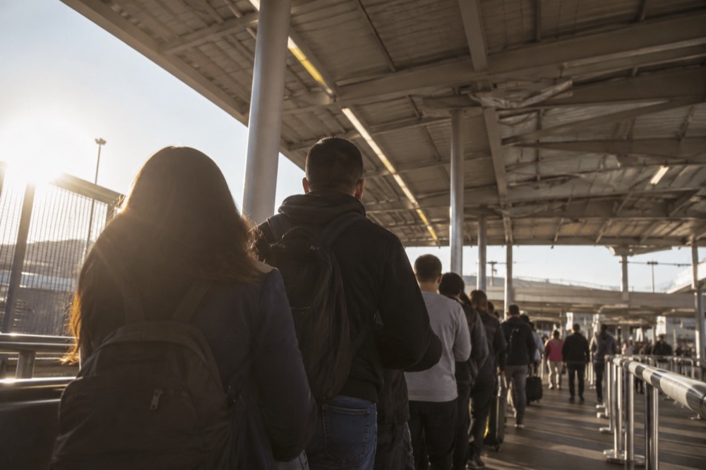 Queue of pedestrians waiting in line inside a covered border crossing facility