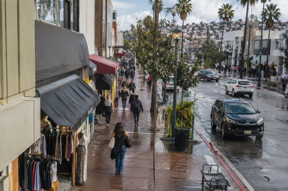 Busy pedestrian shopping street with storefront awnings and banners in Tijuana
