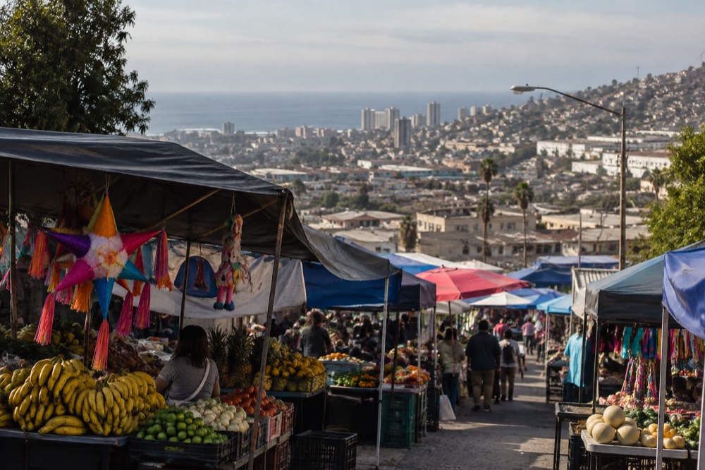 Open-air market stalls with fresh produce and hanging piñatas under warm light