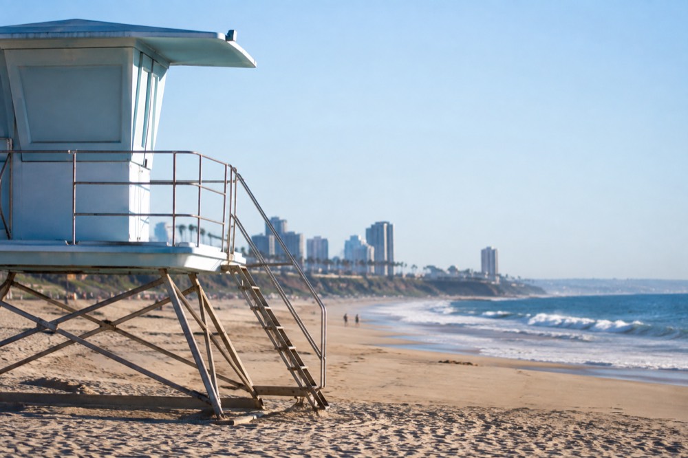 Lifeguard tower on a wide beach with a small breaking wave and clear sky