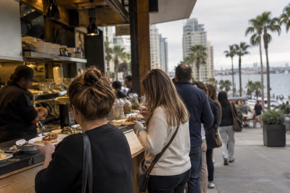 A guided food tour group sampling dishes at an open restaurant counter