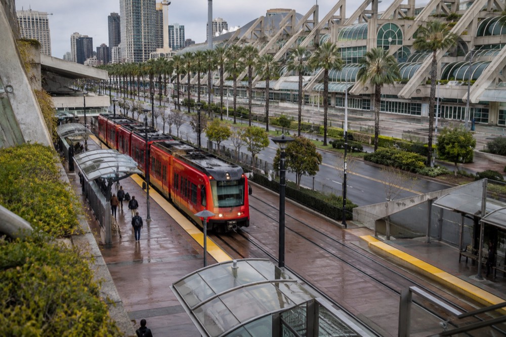 Red trolley arriving at a downtown station with the convention center visible beyond