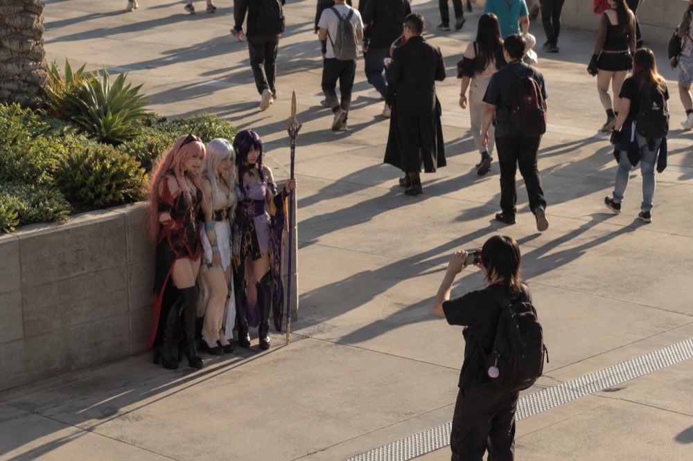 Costumed attendees posing for photos on a sunny downtown sidewalk