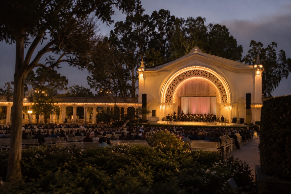 A historic organ pavilion building lit up at night with an open-air concert stage