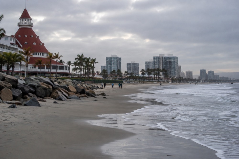 Very wide beach with soft sand and gentle waves beside a historic wooden hotel