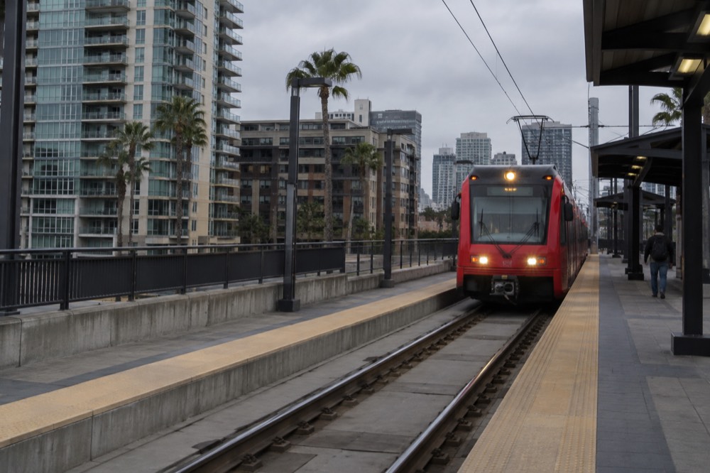 A red trolley arriving at an elevated station platform in downtown San Diego