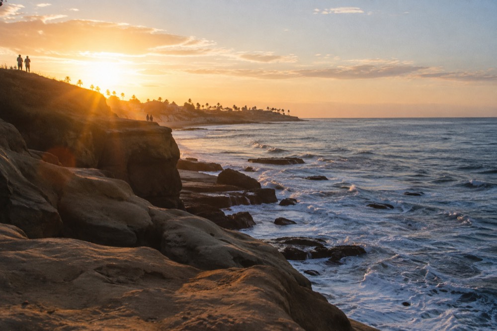 A quiet ocean cliff edge with rock formations and waves below at golden hour