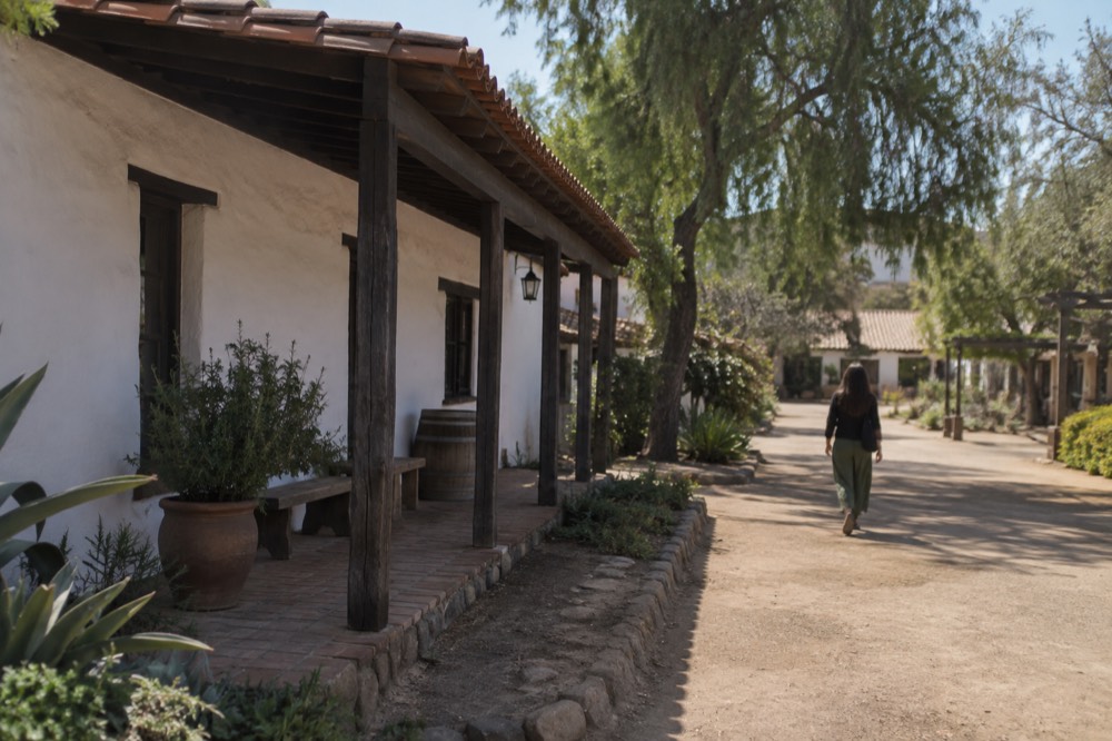 A historic adobe building with a white plastered wall and wooden porch in an old town plaza