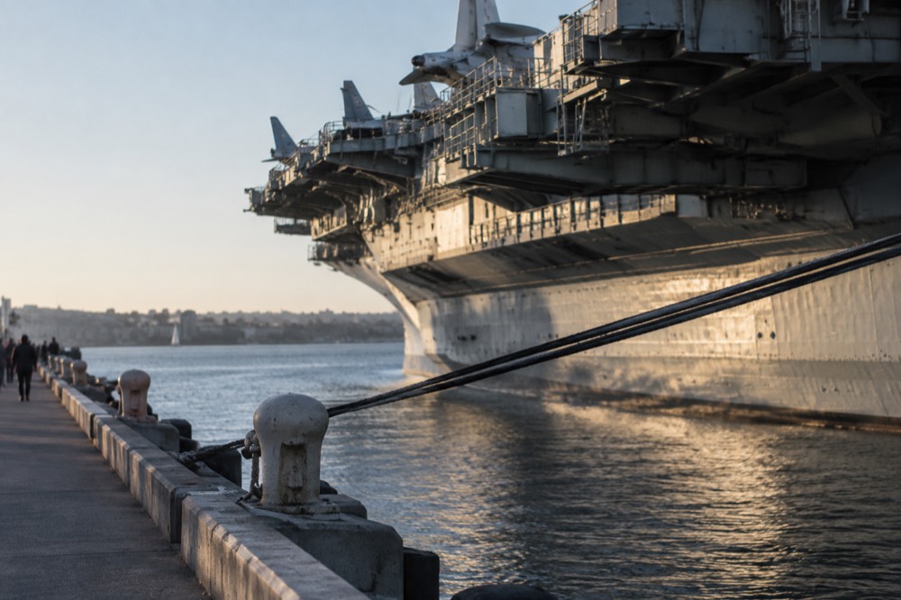 A historic aircraft carrier museum ship moored at a downtown waterfront dock