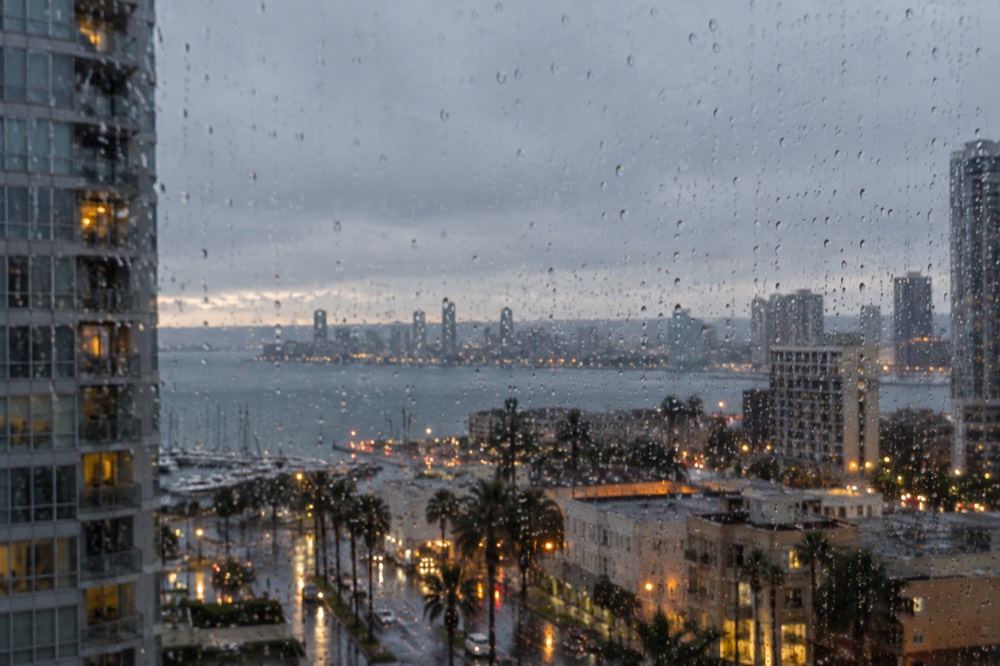 Rain droplets on a window with blurred city lights beyond at dusk