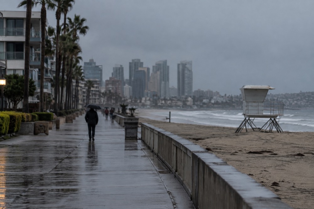 Empty beach boardwalk under rain with gray ocean and closed lifeguard tower