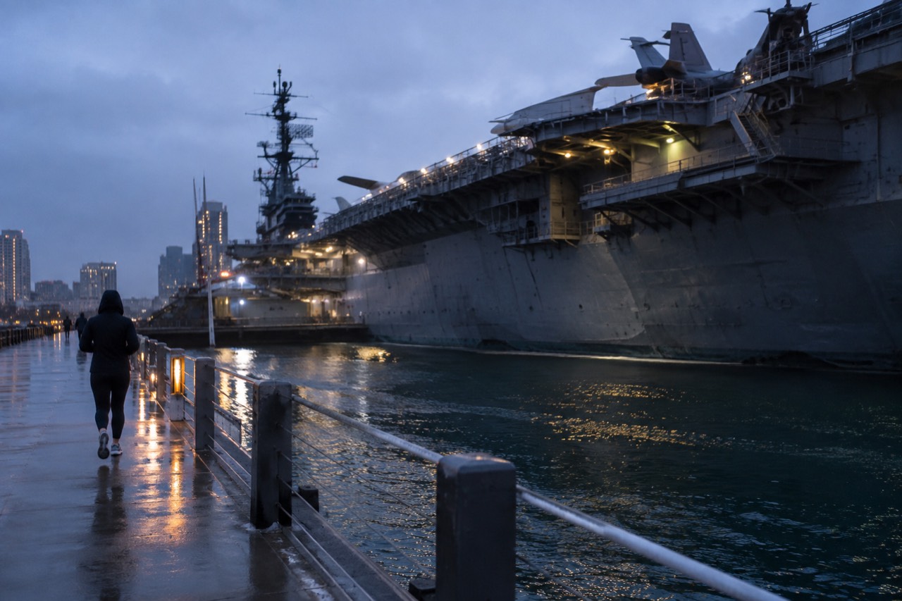 Rain streaked windows overlooking San Diego harbor with the USS Midway flight deck in the distance