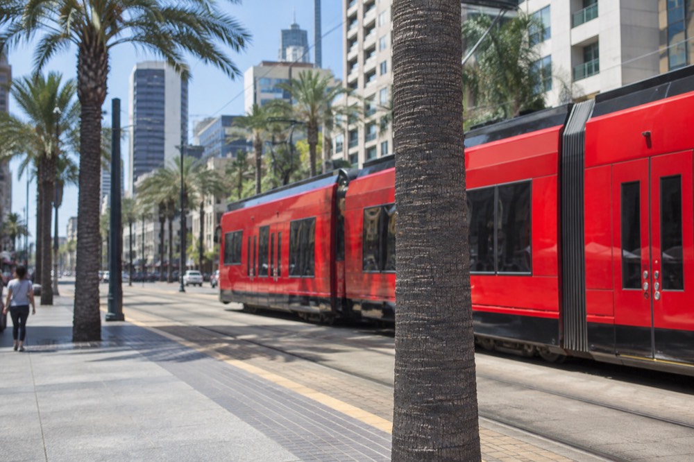 Red trolley car traveling along a downtown San Diego street