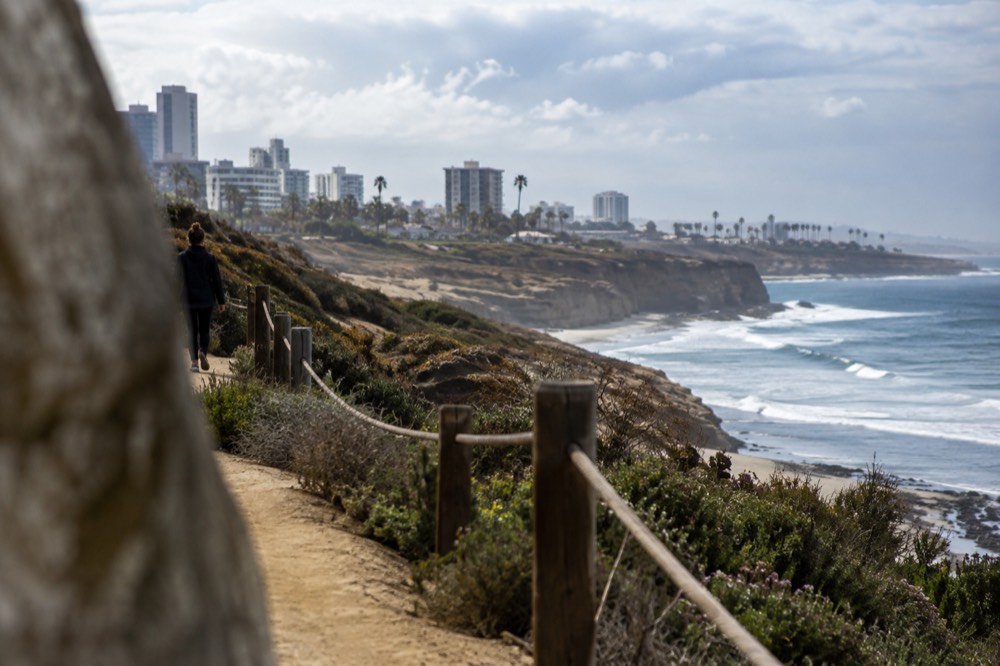 A narrow dirt trail running along a windswept coastal bluff above the ocean