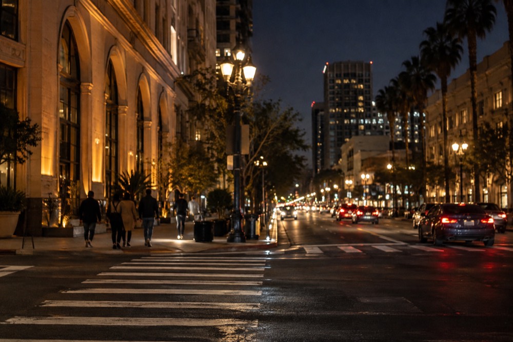 A city street at night with lit historic buildings and a lit pedestrian crossing