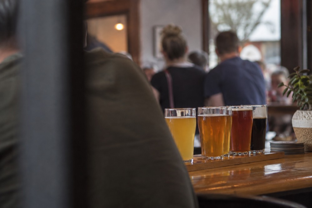 Glasses of craft beer lined up on a wooden bar top in a warm taproom