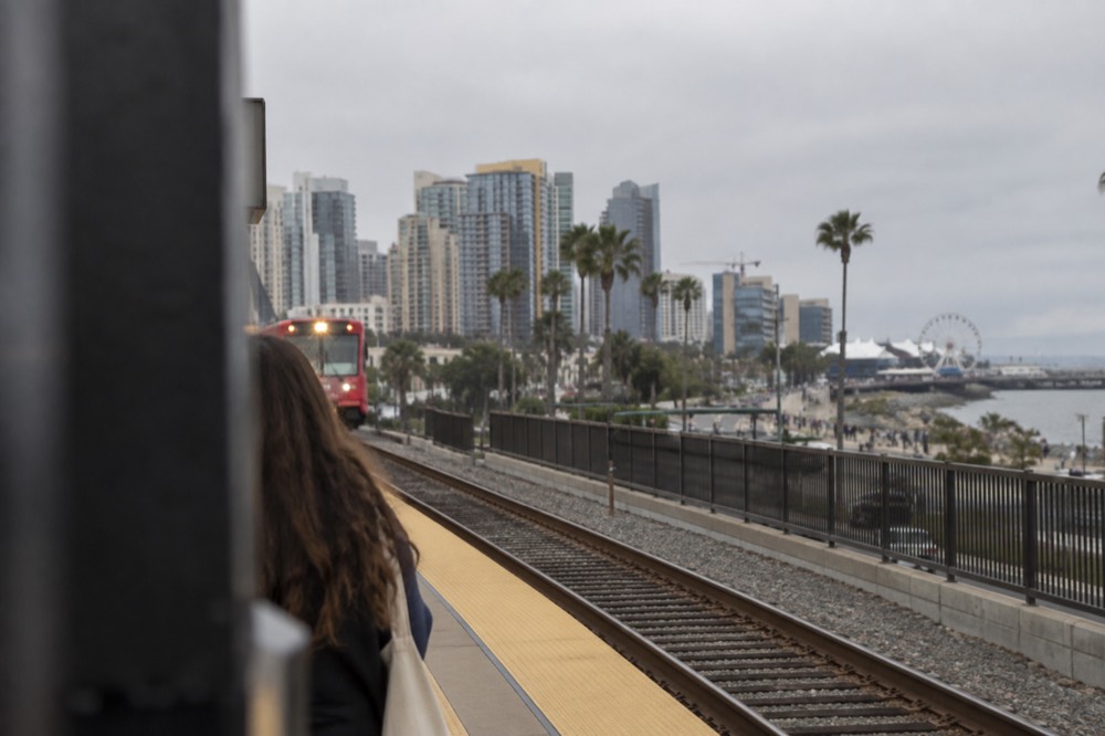 Commuter train platform near coastal bluffs with a fairground in the distance