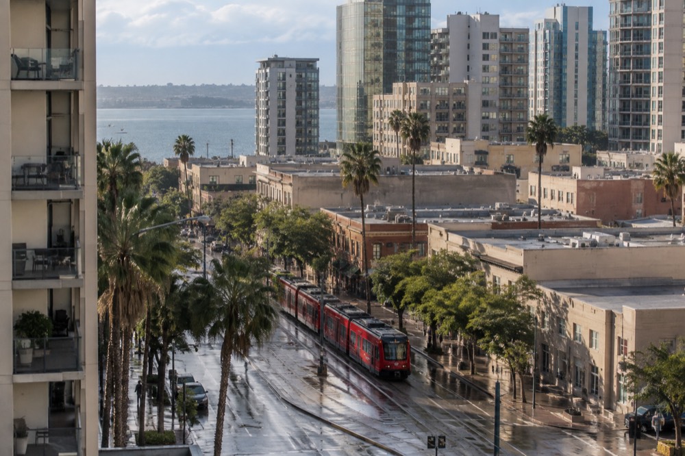 A red trolley car passing low buildings on a downtown street