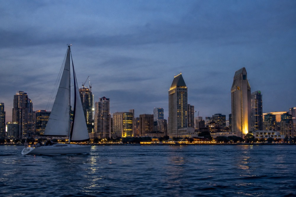 Sailboat passing city lights on San Diego Bay in the evening