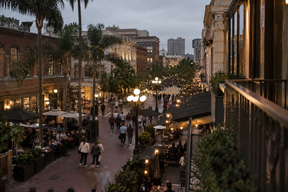 Evening crowd on a lit pedestrian street with outdoor tables in San Diego