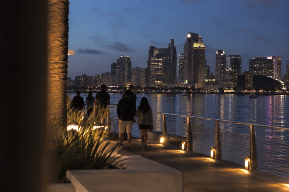 City lights reflecting on San Diego Bay water at night with a lit promenade