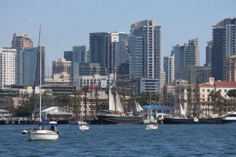 Historic tall ships and sailboat masts in the harbor in front of city towers