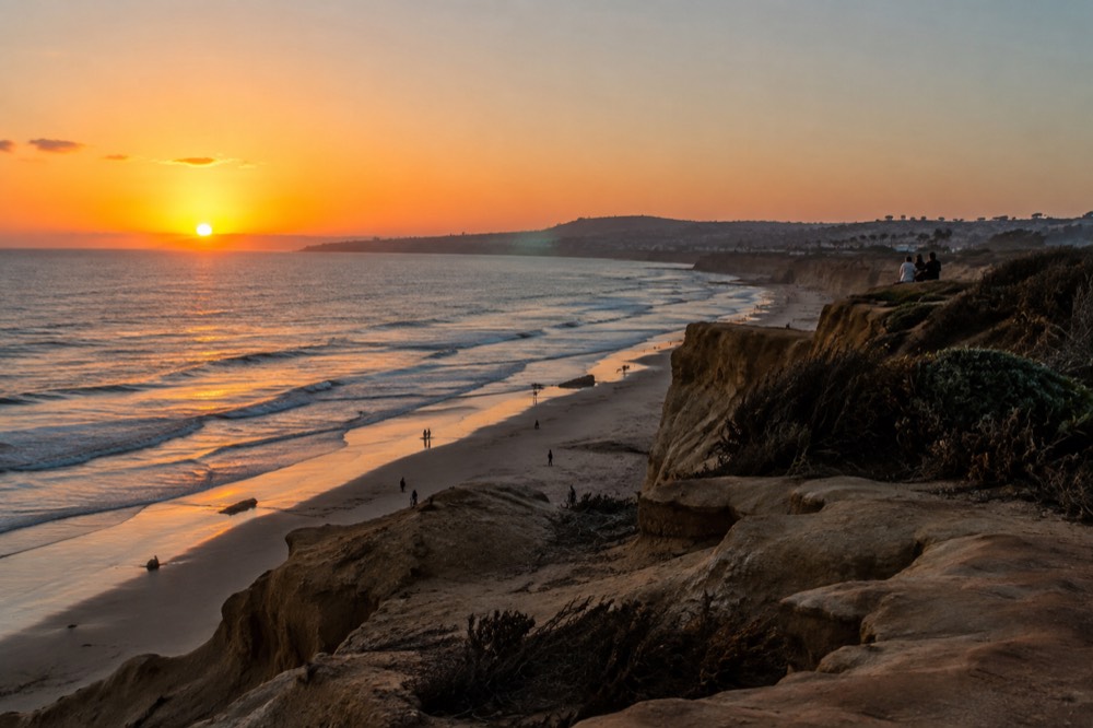 Sun setting over the Pacific Ocean as seen from a sandstone cliff edge