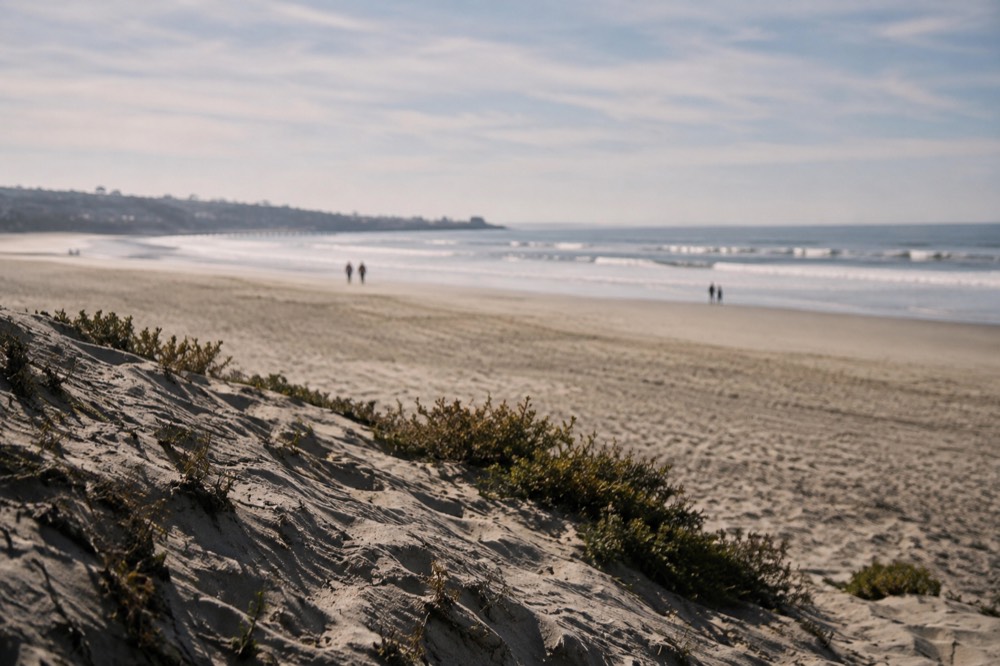 Calm morning ocean with small waves breaking near a wide empty beach