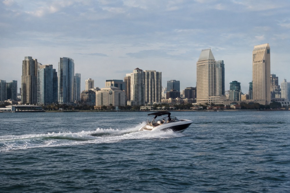 A speedboat carving a turn across San Diego Bay with the city skyline behind it