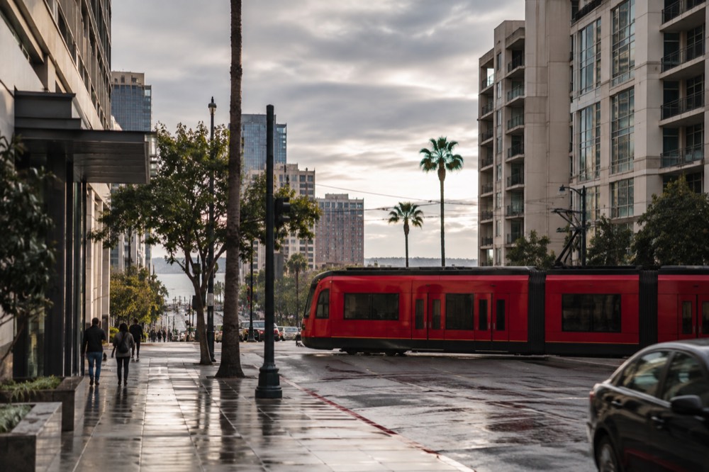 Red trolley crossing a downtown San Diego street in the late afternoon