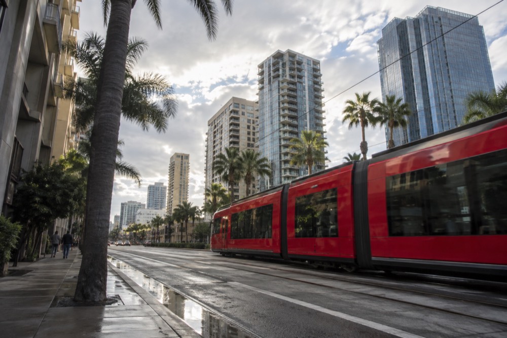 Red San Diego trolley passing through a downtown street on a mild day