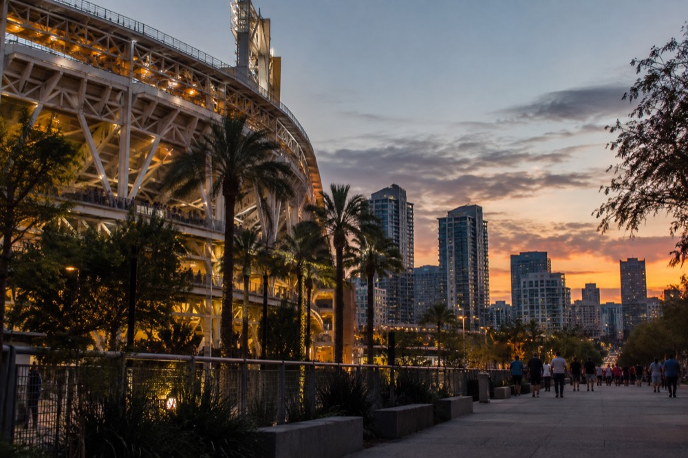 Baseball stadium exterior at dusk with the downtown skyline behind it