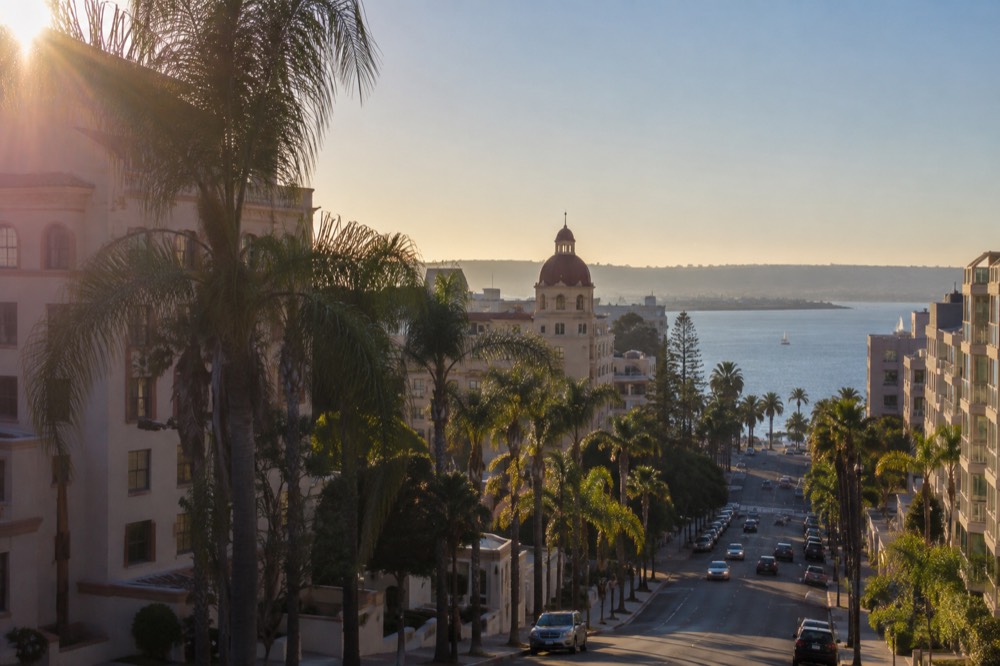 Palm-lined street with a historic hotel in the background under a clear sky