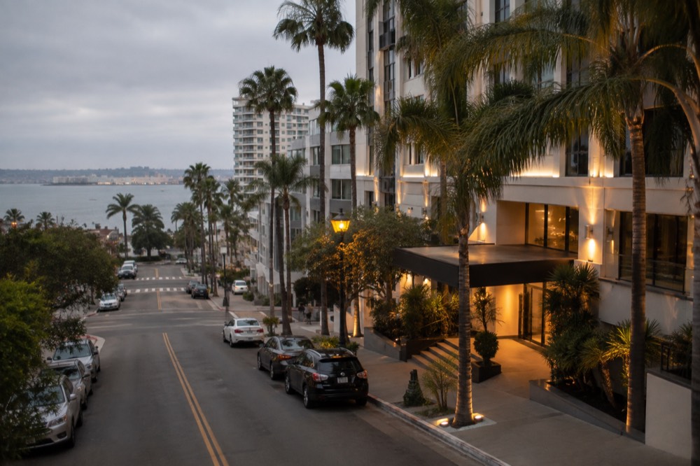 Boutique hotel entrance with palm trees and evening lighting on a quiet street