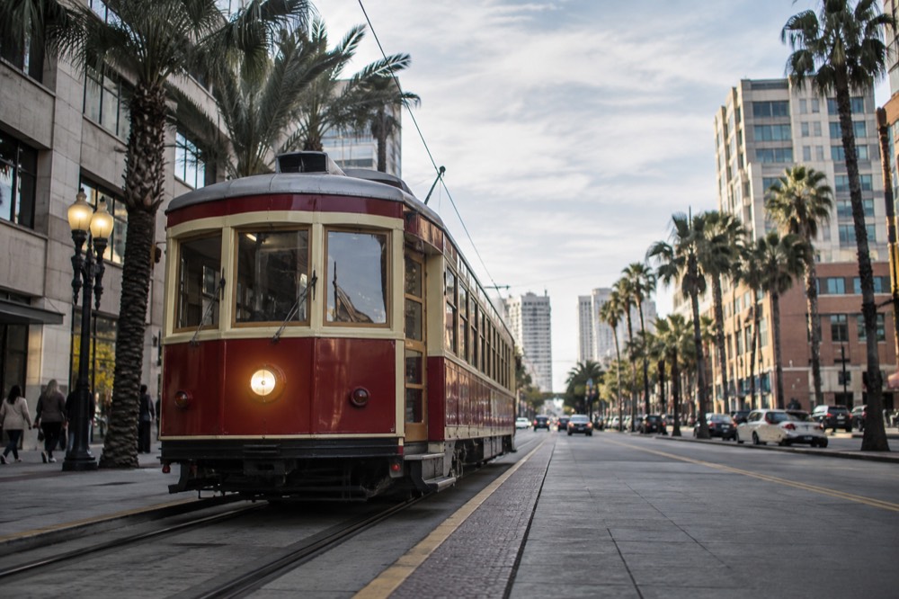 Historic trolley stopped on a downtown San Diego street with palm trees