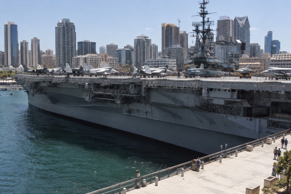 USS Midway aircraft carrier flight deck with restored jets and downtown skyline behind