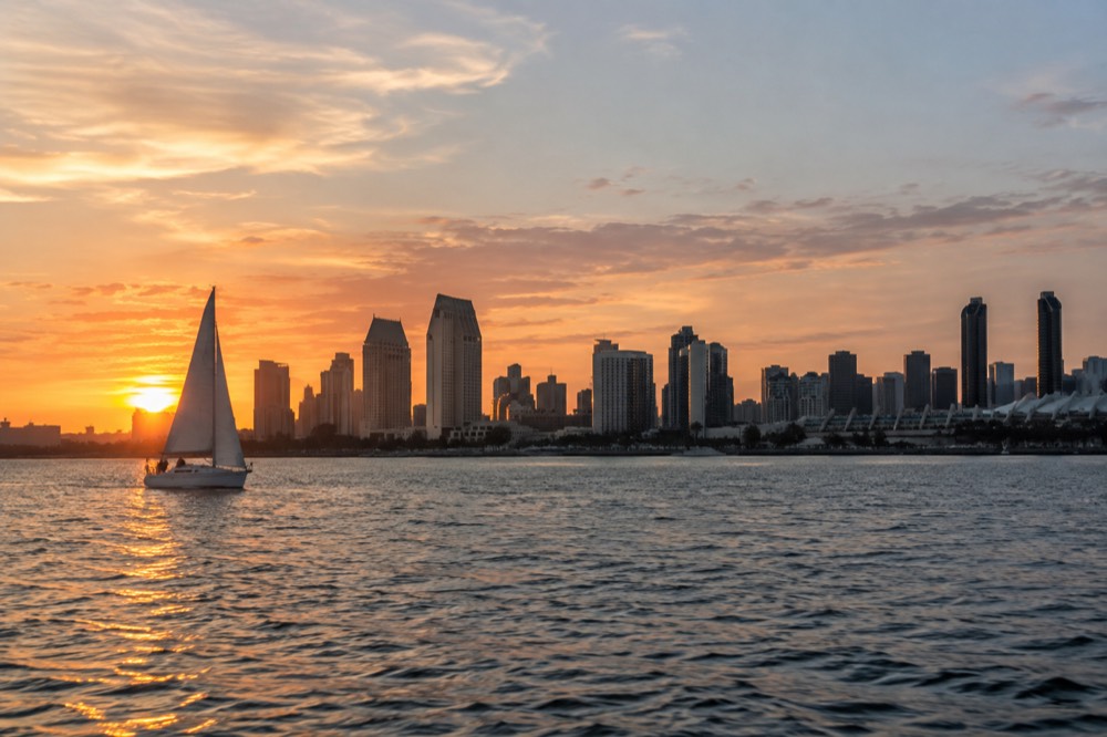 Sailboat on San Diego Bay at sunset with the downtown skyline glowing