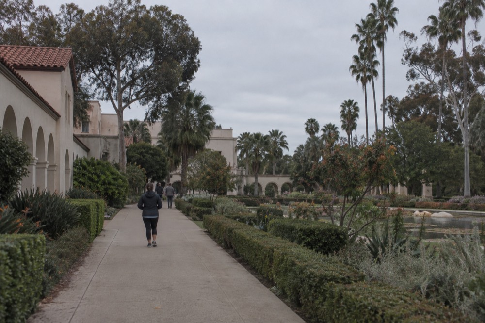 Gardens and Spanish colonial style buildings along a walkway in Balboa Park