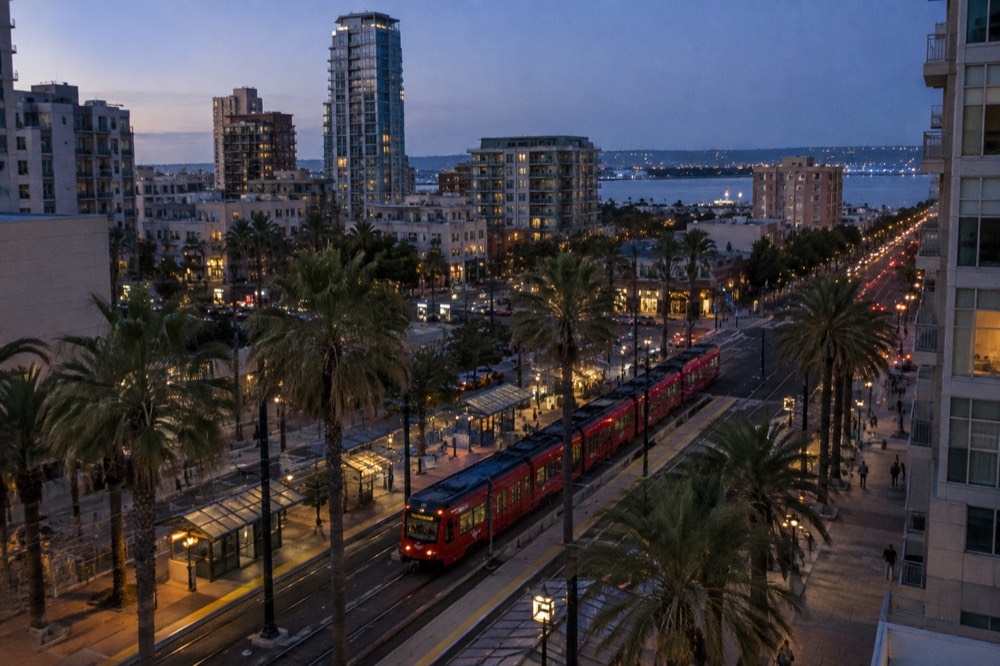 A red trolley at a downtown station with palm trees
