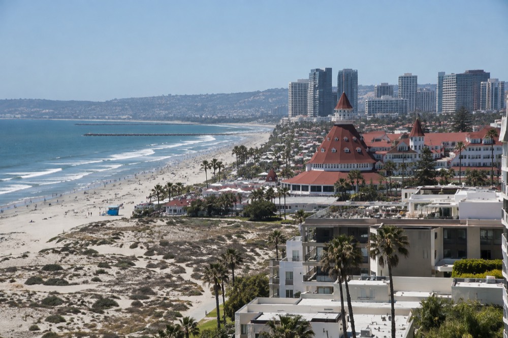 Wide sandy beach with a red-roofed wooden hotel building behind the dunes