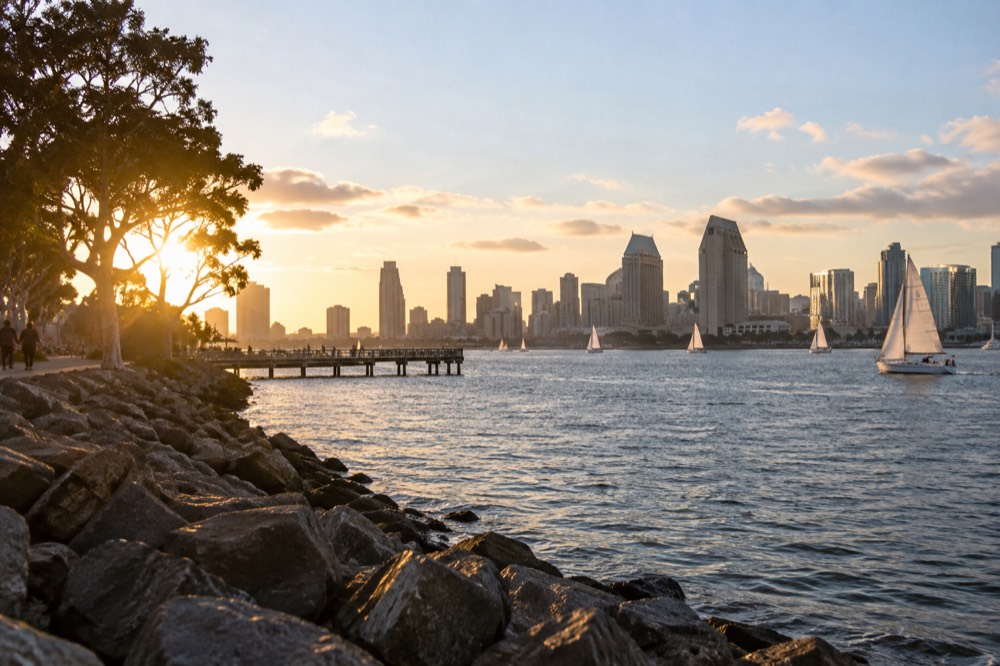 Harbor water with sailboats and a city skyline at golden hour