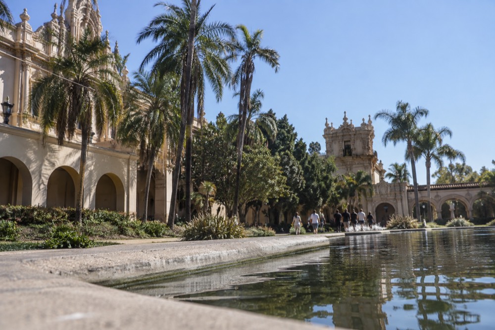Gardens and ornate Spanish colonial buildings along a tree-lined promenade in a large urban park
