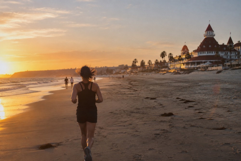 A historic hotel with red turrets beside a wide empty beach at golden hour